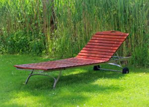 drewniany leżak ogrodowy ustawiony na trawie